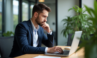 Jeune homme en costume examinant son ordinateur avec symboles crypto